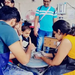 Even the littlest hands can create. Here, a young child experiences the magic of the pottery wheel with the help of an adult, his eyes full of curiosity.
