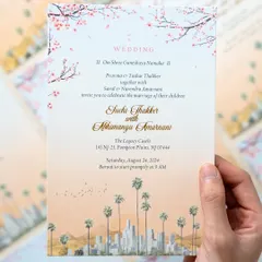 A hand holding the main wedding invitation for a Los Angeles ceremony. I illustrated the city's iconic skyline with palm trees in the foreground and cherry blossoms above, blending urban and natural elements beautifully.