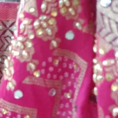 A detailed look at the mirror and thread work on a bright pink fabric. I take pride in the fine details that make each outfit unique.