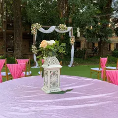 A close-up of a table centerpiece at an outdoor wedding. The decorative white lantern and fresh flowers add a touch of elegance to the guest seating, tying into the overall rustic theme.