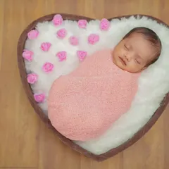 For my posed newborn sessions, I use a variety of props like this heart-shaped basket. I ensure your baby is safely and comfortably swaddled, creating a peaceful and adorable portrait.