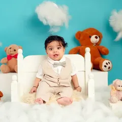 A classic portrait of a baby boy in a smart vest and bow tie. The fluffy clouds and teddy bears create a dreamy, playful atmosphere.