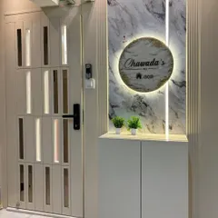 This elegant entrance in Bhayandar features a backlit nameplate set against a marble-finish panel. The design includes a sleek, floating shoe cabinet and a custom safety door with vertical slats.