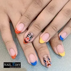 A fun and quirky set featuring hand-painted sad and happy clown faces. We paired the character art with bold, colorful French tips in orange, yellow, and blue to create a playful, mismatched manicure.