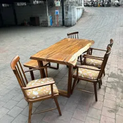 A rustic dining set featuring a live-edge solid wood table. The set is completed with a matching bench and classic spindle-back chairs, perfect for a warm, family-style dining room.