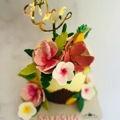 A beautiful tropical-themed smash cake for a first birthday. It's decorated with handcrafted, edible hibiscus flowers and pineapples.