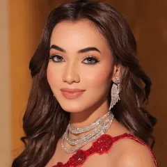A close-up on red carpet beauty. The styling focuses on flawless makeup and a stunning multi-layered diamond necklace that perfectly complements the vibrant red of the gown.