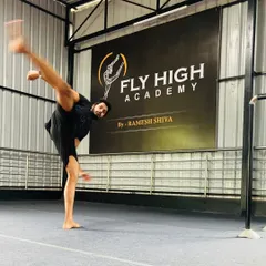 A student executes a high kick in front of the Fly High Academy banner. This powerful image captures the spirit of our training.