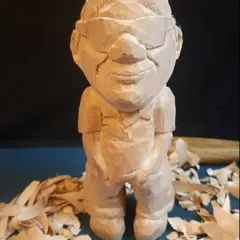 This is what a figurine looks like after the carving is complete but before any paint has been applied. You can see the raw, textured wood and the pile of wood shavings that are a happy byproduct of my work.