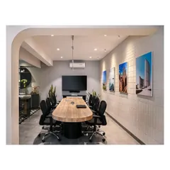 The conference room uses a light color palette and glass walls to bring light into a darker corner of the office. A custom-built table and clay tile walls create a sophisticated and functional meeting space.