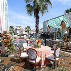 The dining area under a canopy of aqua drapes and hanging foliage, with tables dressed in colorful, printed tablecloths.