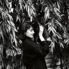 A tender moment between a woman and a cat. Black and white photography enhances the feeling of quiet connection and the simple joy found in these chance encounters.