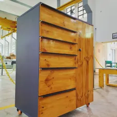 A side view of the student-made cabinet, showing the contrast between the dark grey panel body and the warm, natural grain of the finished pine wood.