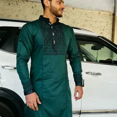 A happy client in a custom-made dark green kurta. This piece features detailed black threadwork on the neckline and cuffs, showcasing our ability to add personalized embroidery to a classic kurta design.