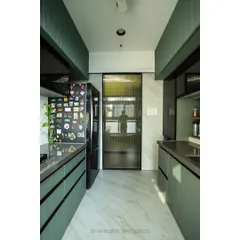 Another view of the sage green kitchen, showing the seamless integration of the refrigerator and the use of a smoked glass door to separate the utility area.