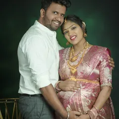 An elegant studio portrait of a couple dressed in traditional attire. The intricate details of the silk saree and gold jewelry are captured beautifully, creating a timeless family heirloom.