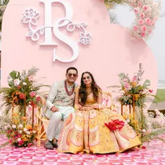 A chic and modern Mehndi or Haldi setup with a personalized monogram on a pink backdrop. The mix of pastel and bright florals gives it a fresh, contemporary feel.