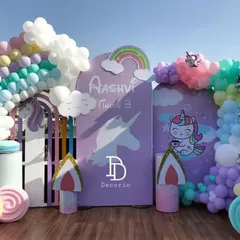 A dreamy unicorn and rainbow themed party for a 3rd birthday. This outdoor setup features pastel rainbow balloon arches, unicorn cutouts, and fluffy balloon clouds, creating a magical atmosphere.