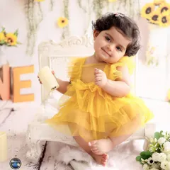 A close-up portrait within the sunflower set, highlighting the baby's adorable expression and outfit.