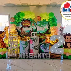 A classic Jungle Book theme for a second birthday. The stage is set with a lush green balloon arch, character cutouts of Mowgli, Baloo, and friends, and large marquee letters and numbers for a personalized touch.