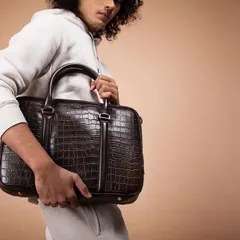 This studio shot for Eske Global focuses on a men's crocodile-texture laptop bag. The styling is casual yet sharp, showing how the luxury accessory fits seamlessly into a modern professional's wardrobe.