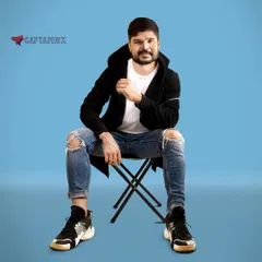This seated portrait offers a different perspective for a men's fashion portfolio. The direct, confident pose against the blue studio background is ideal for demonstrating versatility to casting agents and brands.