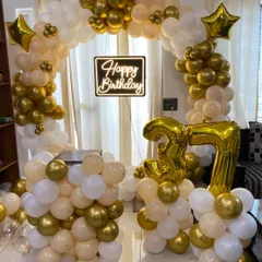 An elegant 37th birthday setup with a circular balloon arch in cream, white, and gold. The decor is completed with a neon sign and gold foil number balloons.