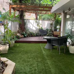 Even ground-floor spaces can become serene backyard getaways. Here, we combined a manicured lawn with a shaded wooden deck and pergola, surrounded by greenery to create a perfect spot for relaxing or entertaining.