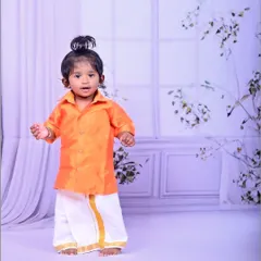A little boy in a traditional South Indian dhoti and shirt, looking absolutely adorable.