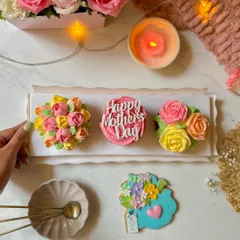 A trio of my Mother's Day floral cupcakes, showcasing different hand-piped flower designs from roses to tulips. Each one is a testament to the delicate artistry I bring to my baking.