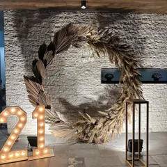 We created this stunning birthday photo backdrop using a large circular frame adorned with dried palm leaves and pampas grass, with a custom neon sign and marquee lights.