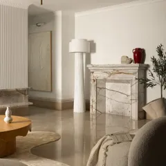 This view of the Ecru Maison living room showcases the harmony between different elements. A classic marble fireplace provides a timeless anchor, while the modern boucle armchair and sculptural floor lamp introduce soft curves and contemporary elegance.