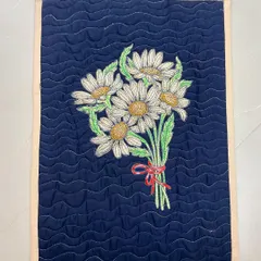 This quilted placemat features a lovely embroidered bouquet of daisies, finished with a wavy quilting pattern.