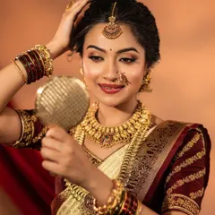 A happy bride-to-be trying on a classic temple jewellery set. This one features a beautiful coin haaram and a detailed choker, paired with a traditional nose ring and maang tikka.