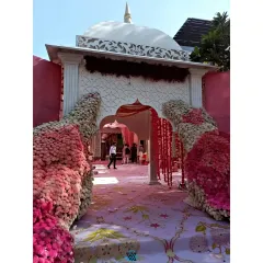 A closer look at the entrance pathway, showing the dense floral work and the intricate patterns on the custom built structure. Every detail is planned to create an immersive and beautiful experience for everyone attending the Sikh wedding ceremony.