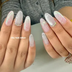 An ethereal and glamorous set of long almond nails, featuring a soft ombré base with a sparkling glitter fade and rhinestone accents.