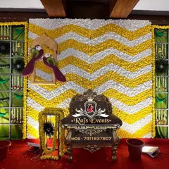 This traditional baby shower backdrop features a chevron pattern of white and yellow flowers, flanked by panels with intricate floral arrangements and peacock motifs.
