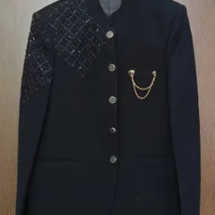 A closer look at this black Jodhpuri-style suit jacket. It features a mandarin collar, intricate shoulder beading, and a pocket chain for a touch of regal flair.
