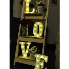 A simple and romantic detail for a date night at home. We used this wooden ladder shelf to display light-up 'LOVE' marquee letters and small floral arrangements, adding a warm and loving touch to the space.