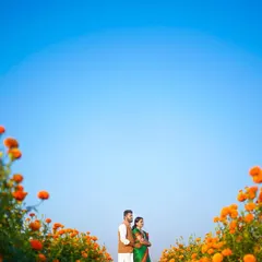 Using the vast blue sky and the vibrant orange of the marigold field to frame the couple. This wide-angle shot creates a sense of scale and beauty, making the couple the central focus in a breathtaking landscape.