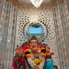 This setup shows how a Ganpati idol can be placed against an existing modern interior. The home's patterned mirror wall serves as a unique and reflective backdrop, enhancing the festive feel without needing a separate structure.