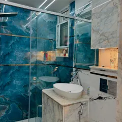 A stunning bathroom renovation featuring a bold blue marble-finish tile. The design includes a glass shower partition and a compact vanity, creating a luxurious and modern look.
