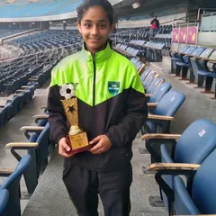 Tanya Singh posing with her well-deserved Top Scorer trophy at the stadium. We support our players at every step, celebrating their victories as a family.