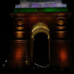 India Gate illuminated in the colors of the national flag. Originally built as a World War I memorial by the British, its meaning has been transformed post-independence into a symbol of the nation and a popular site for both public recreation and protest.