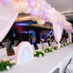 For the unicorn party, we designed a long guest table with a beautiful pastel balloon arch overhead and custom rainbow centerpieces. Every detail is planned to match the theme perfectly.