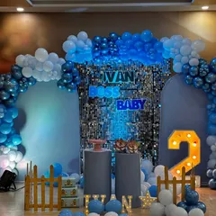 Here is a modern and stylish Boss Baby theme for a second birthday. I used a blue shimmer wall as the central backdrop, framed by a balloon arch in shades of blue and white, with custom neon lettering and a light-up number '2' to complete the look.