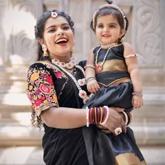 A heartwarming photo of a mother and her baby daughter both dressed in matching black outfits and my custom halwa jewellery for Sankranti.