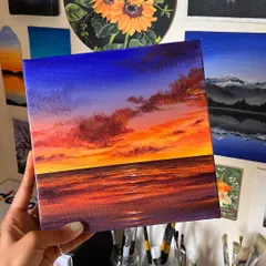 A vibrant sunset painting capturing the deep blues of the sky meeting the fiery oranges and purples of the horizon over the ocean. This acrylic on canvas piece is all about the dramatic and beautiful colors of a beach sunset.