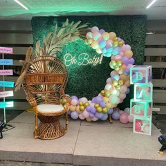 A wider view of the boho-chic baby shower setup, showing the stage, lighting, and decorative signs.