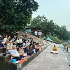 A large group practices guided meditation on the steps of a ghat in Rishikesh. Practicing together in such a powerful natural setting deepens the experience for everyone involved.
